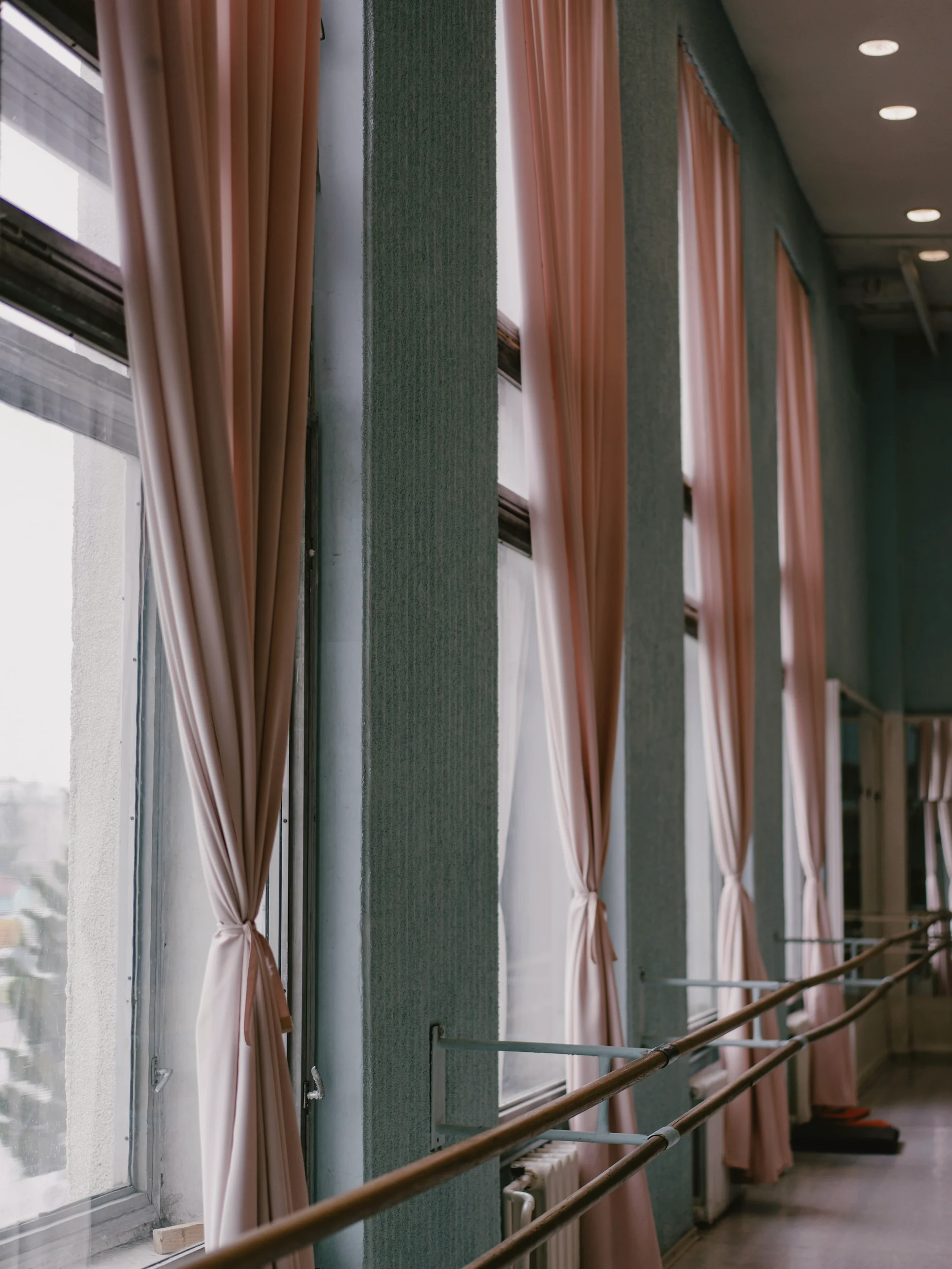 Barra de madera y cortinas rosadas en la sala de Barre